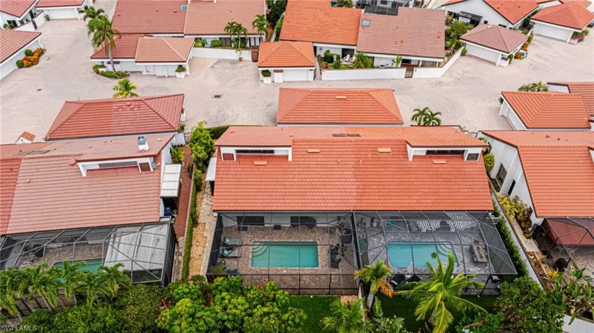 Aerial perspective showcasing two properties, each featuring a private screened-in swimming pool