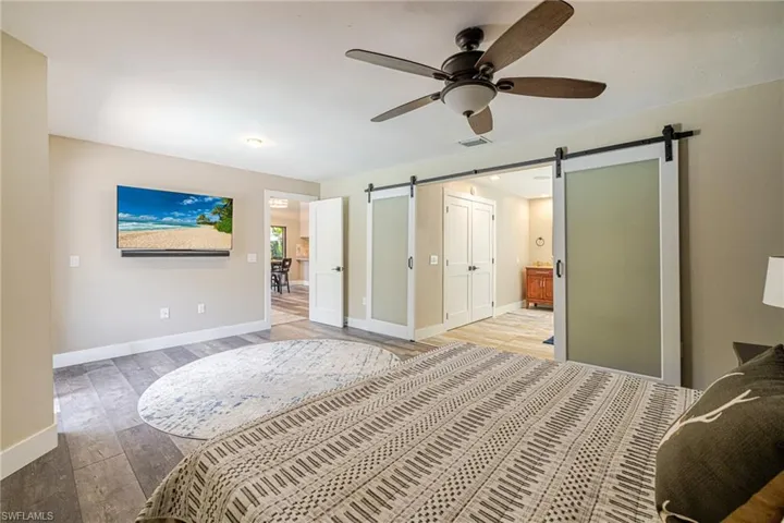 Spacious interior featuring wood-finish flooring, a ceiling fan with light fixture, and a wall-mounted display