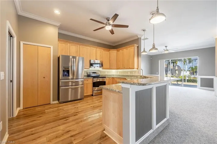 Kitchen featuring kitchen peninsula, pendant lighting, granite countertops,  light brown wood cabinets, stainless steel appliances, and light wood-type flooring