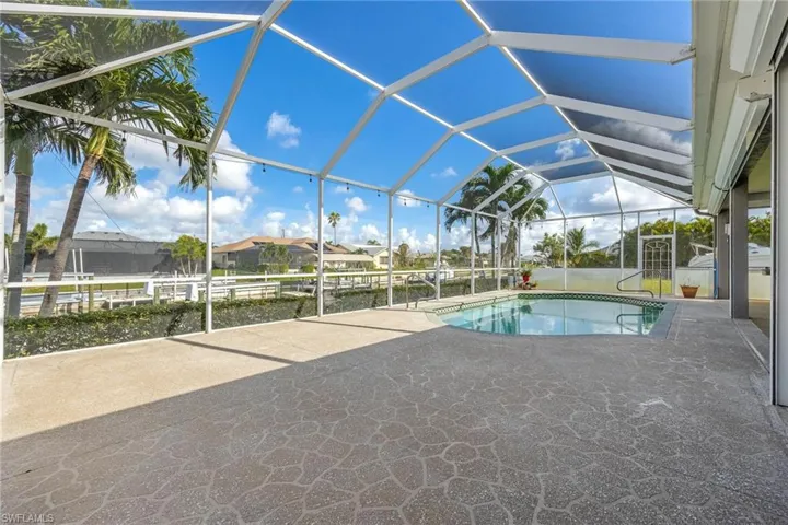 View of pool with pool screen enclosure and a patio area
