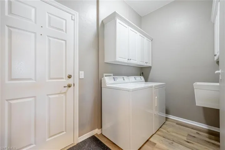 Laundry Room with washing machine and dryer, cabinets, and light wood-type flooring