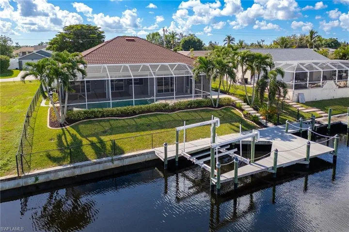 View of dock with a yard, a water view, and a lanai