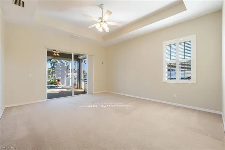 Master Bedroom with plenty of natural light, plantation shutter, and a raised tray ceiling