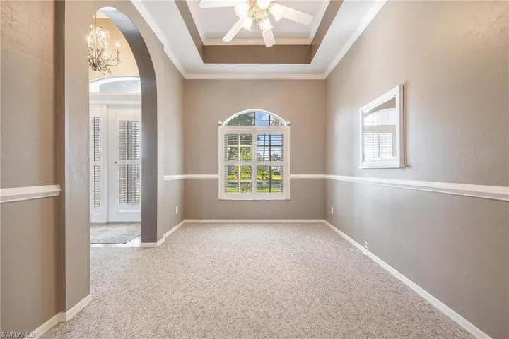 Dining room featuring a tray ceiling, plantation shutters & crown molding