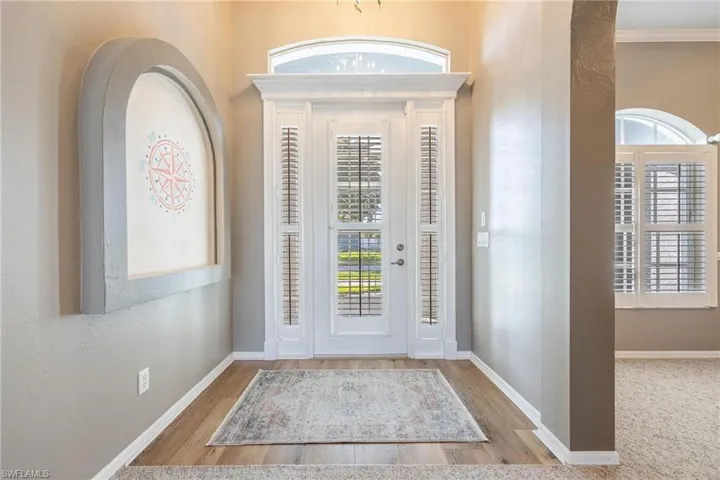 Entrance foyer featuring plantation shutters , crown molding and light wood-style flooring