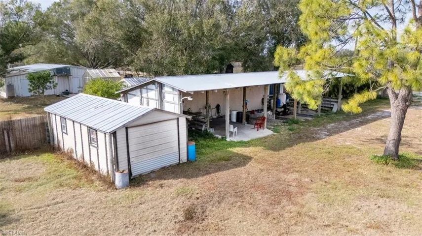 Back of property with a patio area, view of scattered trees, a storage unit, and a garage