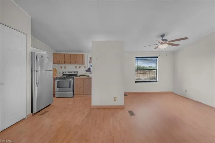 Kitchen with stainless steel appliances, light wood-style flooring, brown cabinets, open floor plan, and a ceiling fan