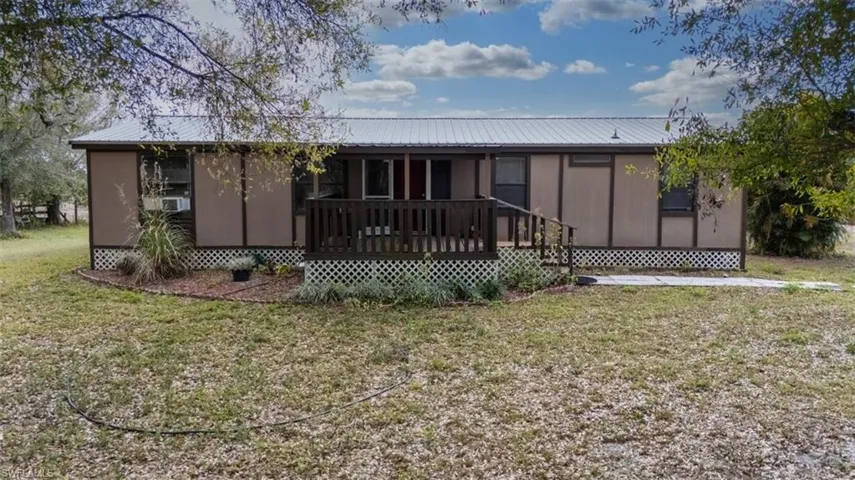 Rear view of house with a wooden deck, a lawn, and a metal roof