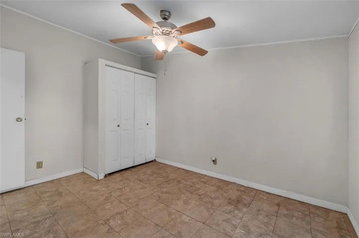 Unfurnished bedroom featuring crown molding, ceiling fan, and a closet