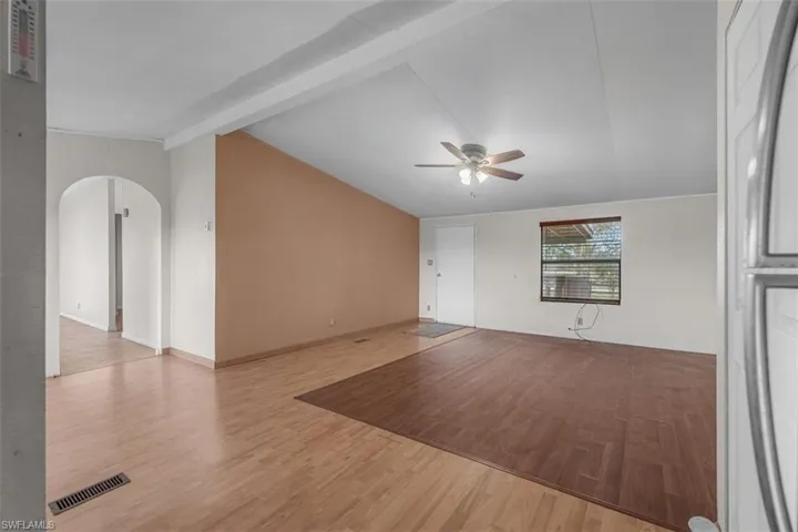 Unfurnished living room featuring light wood-style flooring, arched walkways, and a ceiling fan