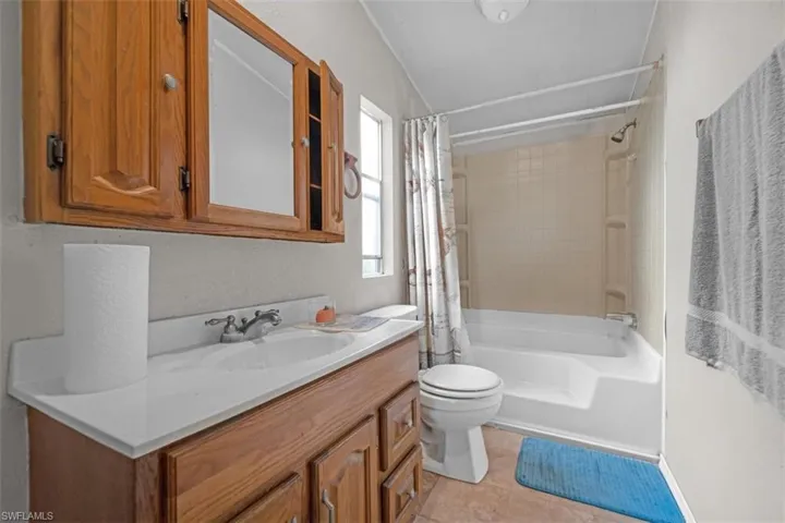 Bathroom featuring vanity, shower / bathtub combination with curtain, and light tile patterned floors