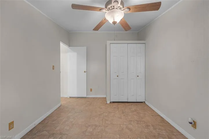 Unfurnished bedroom featuring crown molding, ceiling fan, a closet, and stone finish floors