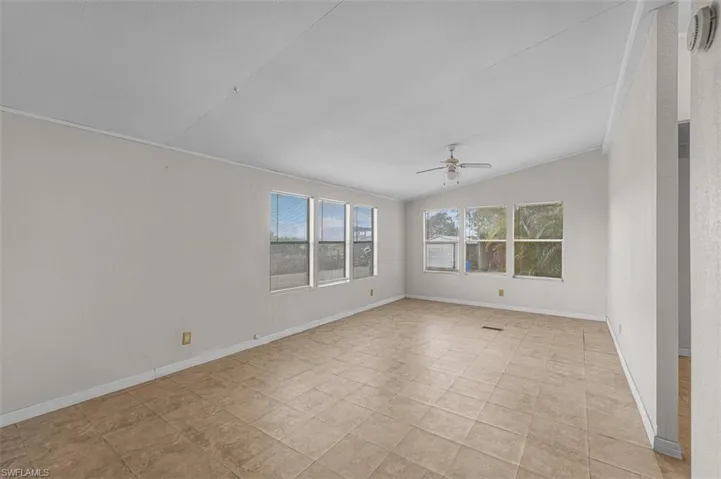 Unfurnished room with lofted ceiling, a ceiling fan, and a smoke detector