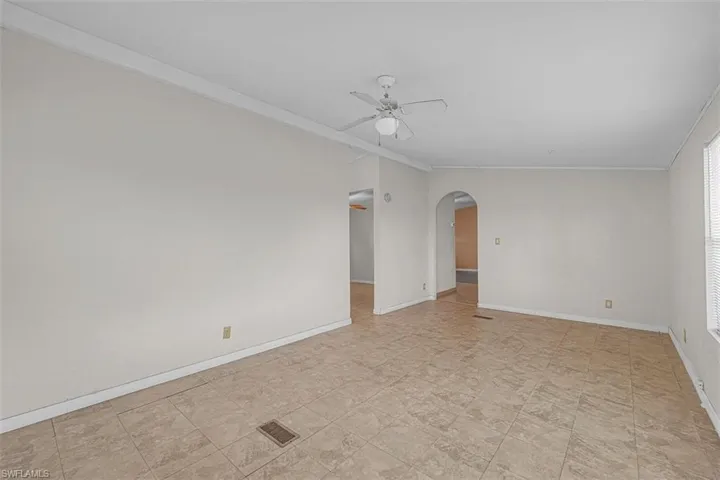 Unfurnished room featuring ornamental molding, arched walkways, and a ceiling fan