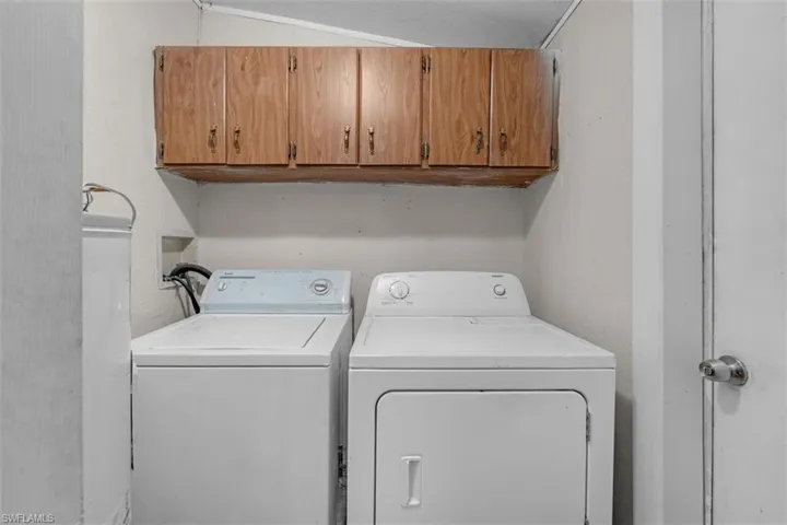 Laundry room with cabinet space, washing machine and clothes dryer, lofted ceiling, and a textured ceiling