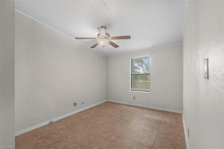 Empty room with ornamental molding, ceiling fan, and a textured wall