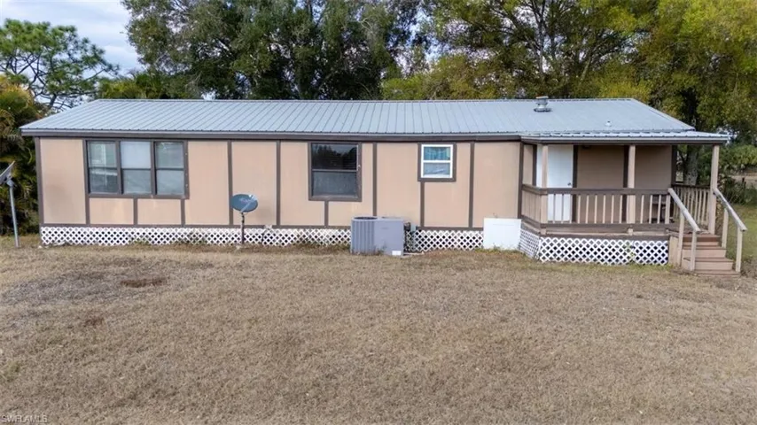View of front of home featuring a deck, a metal roof, and a front lawn