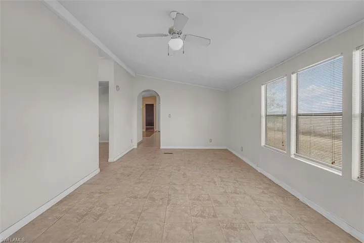 Unfurnished room featuring crown molding, arched walkways, and a ceiling fan