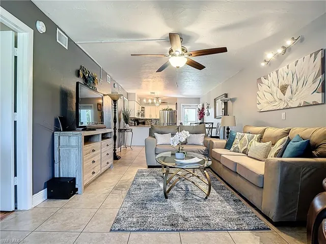 Living area with ceiling fan, light tile patterned floors, a chandelier, and a textured ceiling