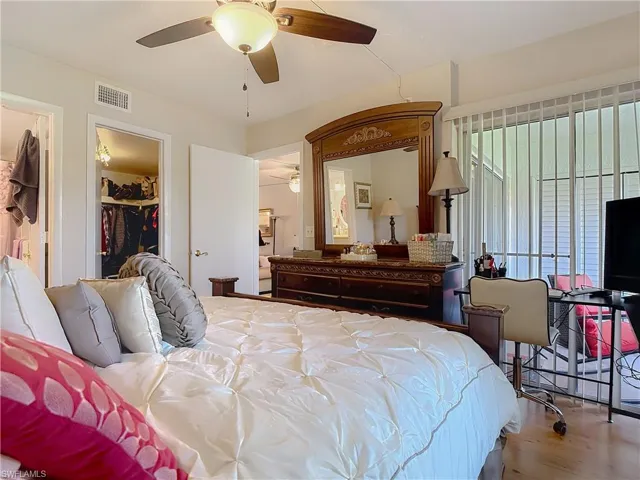 Bedroom featuring wood finished floors, a walk in closet, and a ceiling fan