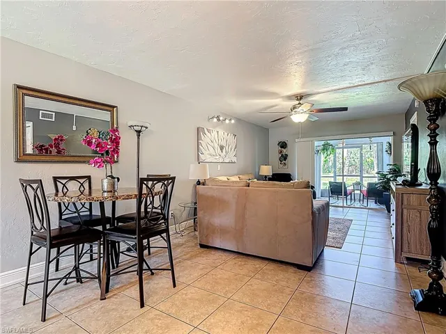 Living room featuring ceiling fan, light tile patterned floors, and a textured ceiling