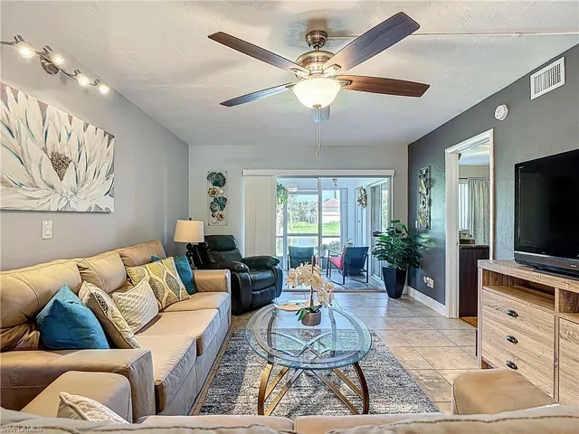 Living area with light tile patterned floors, a ceiling fan, and a textured ceiling