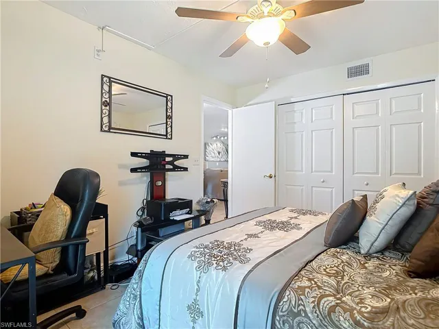 Tiled bedroom featuring an office area, a closet, and a ceiling fan