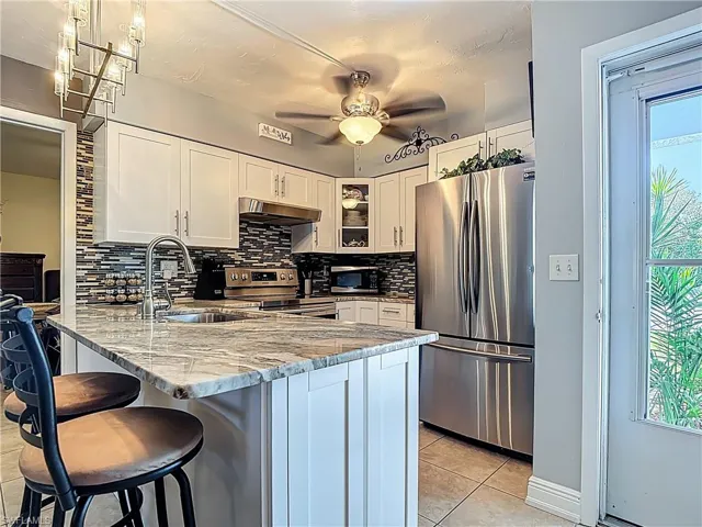Kitchen featuring backsplash, stainless steel appliances, a peninsula, glass insert cabinets, and white cabinetry