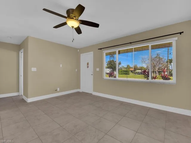 Spare room featuring baseboards, light tile patterned floors, and a ceiling fan