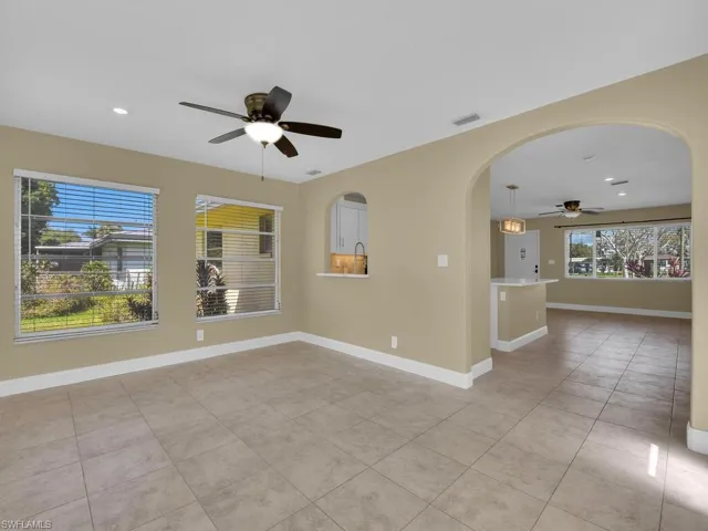 Empty room with light tile patterned flooring, baseboards, ceiling fan, recessed lighting, and arched walkways