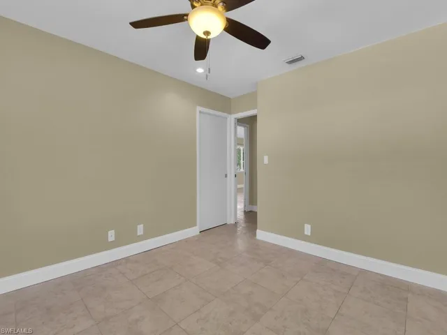 Empty room featuring a ceiling fan, tile patterned floors, baseboards, and visible vents
