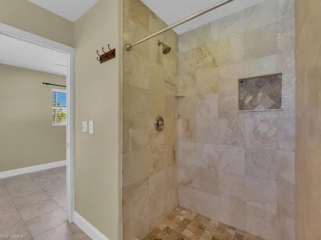 Full bathroom with baseboards, a tile shower, and tile patterned flooring