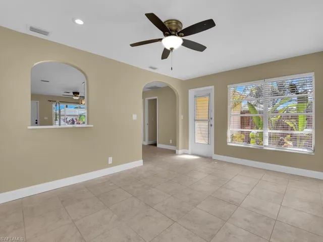 Empty room featuring arched walkways, baseboards, ceiling fan, and visible vents