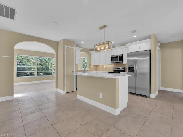 Kitchen with light countertops, stainless steel appliances, decorative backsplash, visible vents, and white cabinets