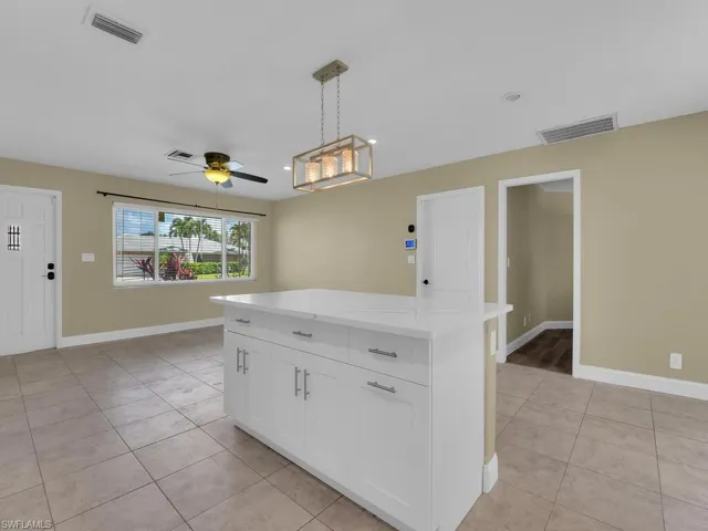 Kitchen featuring decorative light fixtures, visible vents, white cabinets, and baseboards