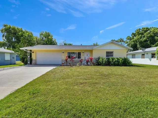 Ranch-style home with driveway, stucco siding, a garage, and a front yard