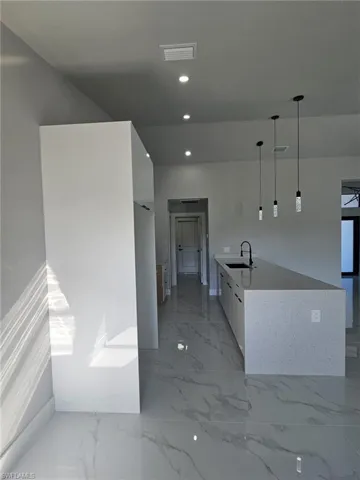 Kitchen with pendant lighting, white cabinetry, and sink