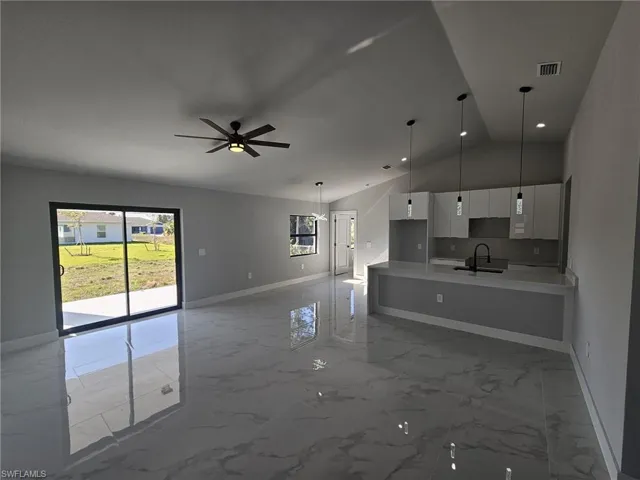 Kitchen featuring pendant lighting, white cabinets, sink, vaulted ceiling, and ceiling fan