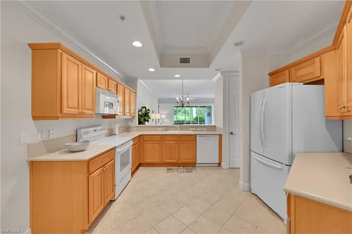 Kitchen with white appliances, ornamental molding, light countertops, a chandelier, and recessed lighting