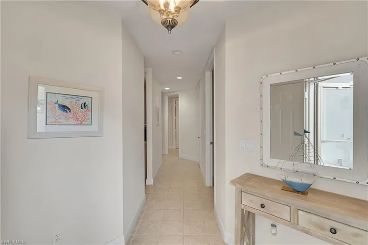 Hall featuring a sink, light tile patterned floors, baseboards, and recessed lighting