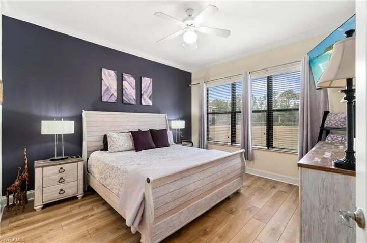 Bedroom featuring light wood finished floors, baseboards, ceiling fan, and crown molding