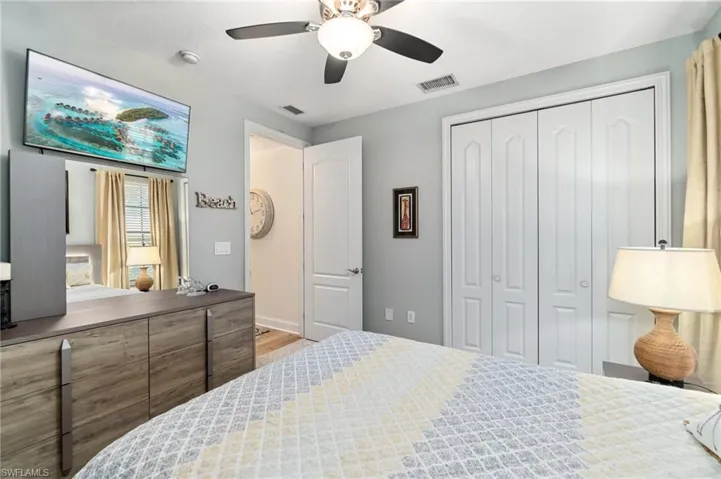 Bedroom featuring a closet, wood finished floors, visible vents, and a ceiling fan