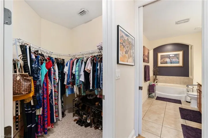 Spacious closet with arched walkways, tile patterned floors, and visible vents