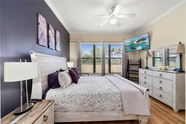 Bedroom with ceiling fan, crown molding, and light wood finished floors