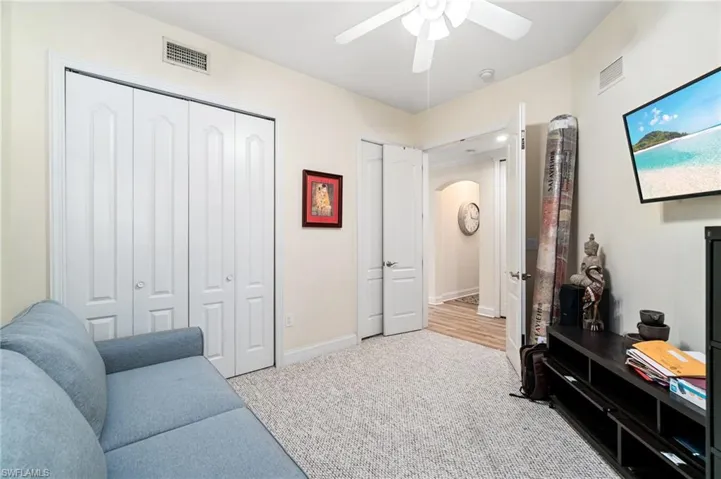Living area with arched walkways, carpet floors, visible vents, and ceiling fan