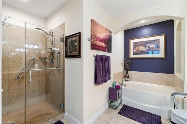 Full bathroom featuring a garden tub, baseboards, tile patterned floors, and a stall shower
