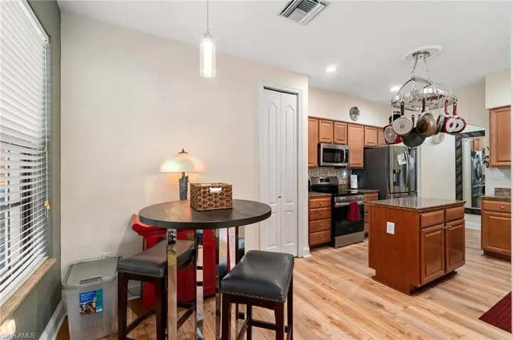 Kitchen with a center island, dark countertops, stainless steel appliances, light wood finished floors, and visible vents