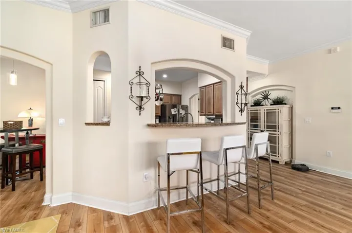 Kitchen featuring light wood finished floors, visible vents, stainless steel refrigerator with ice dispenser, and baseboards
