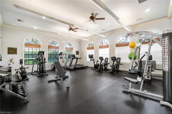 Workout area featuring a ceiling fan, ornamental molding, and visible vents