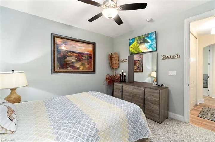 Bedroom featuring light colored carpet, ceiling fan, baseboards, and light wood-style flooring